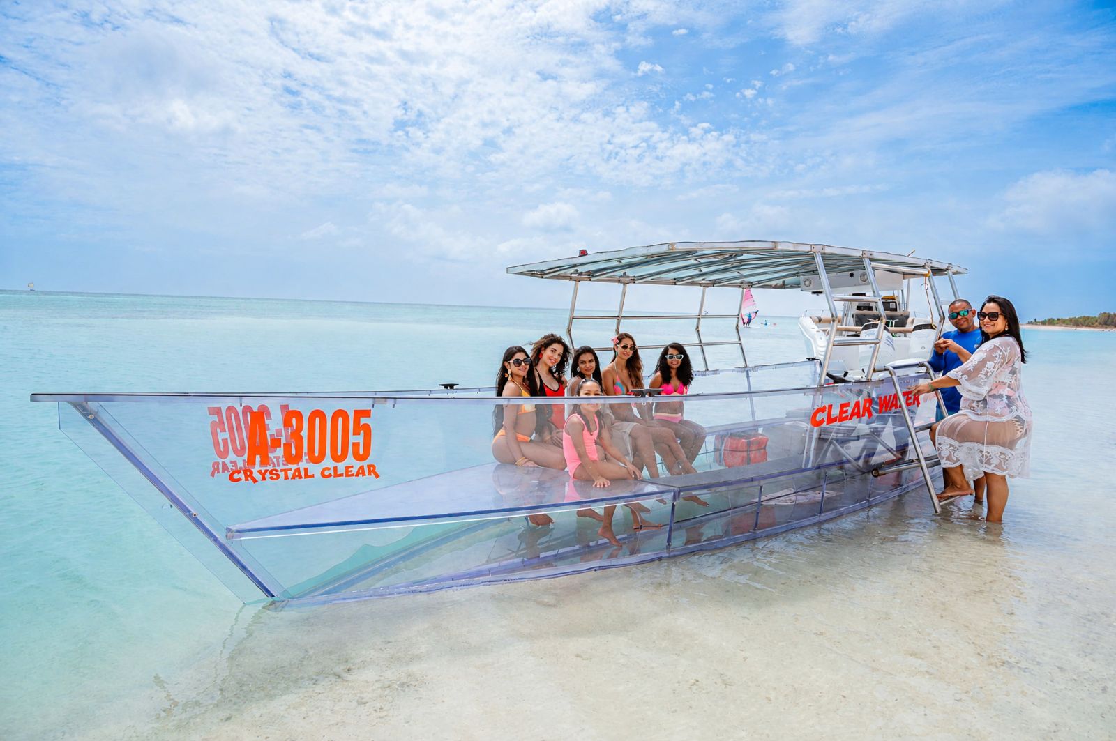 Clear boat with guests in shallow turquoise water